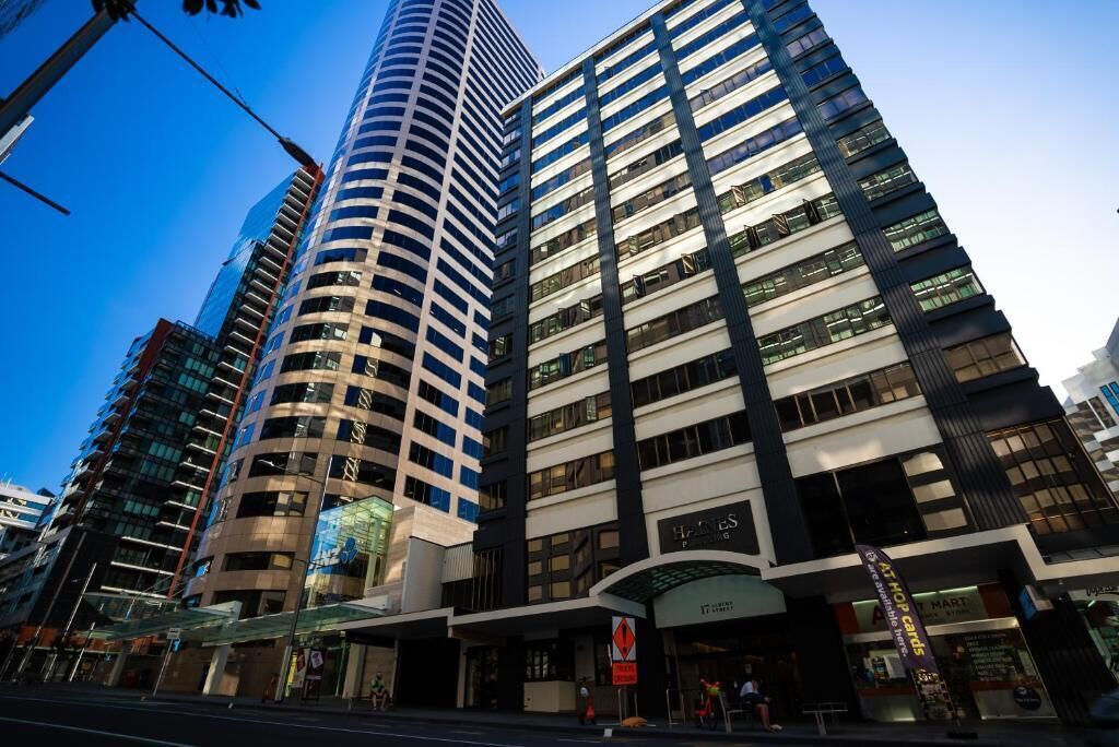 A modern high-rise building with a curved facade, a prominent entrance with a glass canopy, and a visible sign for a hotel.