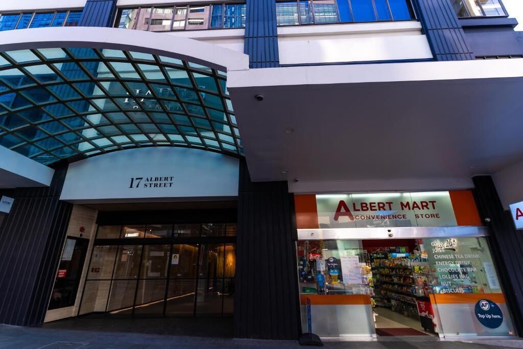 A modern building with a glass facade and a sign for Albert Mart.