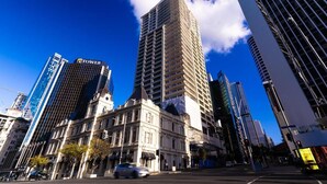 A cityscape with a prominent building labeled 'TOWER' and a historic building with classical architecture. - Garden Hostel (Auckland)
