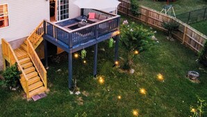 Ein Haus mit einer seitlich angebrachten Terrasse, einer Treppe, die zur Terrasse führt, und einem von einem Zaun umgebenen Garten.