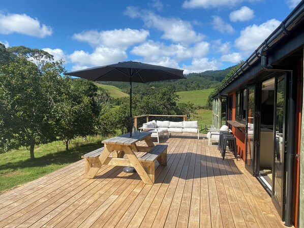 A wooden deck with outdoor furniture, including a table and chairs, and an umbrella.