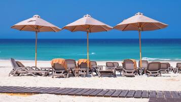 Praia particular, areia branca, guarda-sóis, toalhas de praia