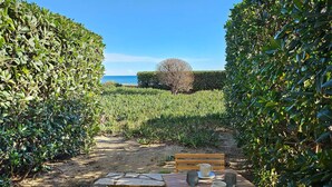 Ein Holztisch mit Stühlen und ein Steinweg, der zum Strand führt.