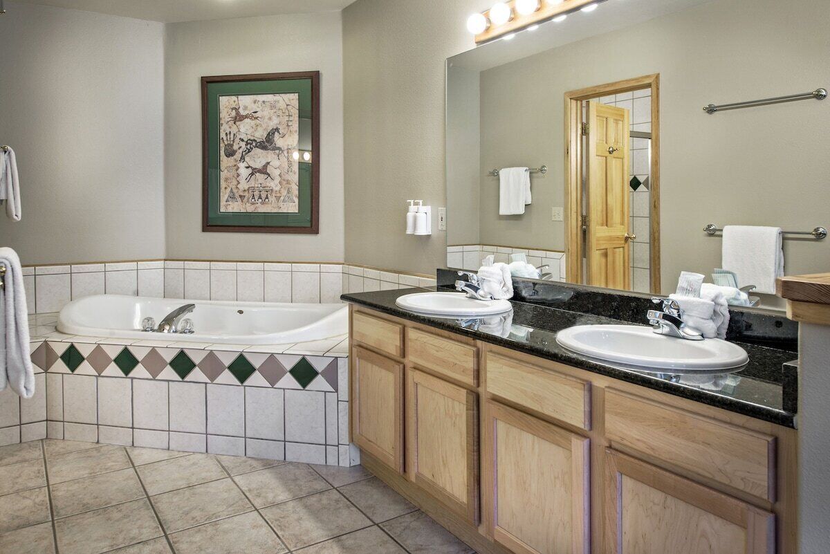 Un bagno con una vasca, due lavandini, un grande specchio e un quadro appeso al muro.