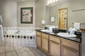Ein Badezimmer mit einer Badewanne, zwei Waschbecken, einem großen Spiegel und einem gerahmten Bild an der Wand.