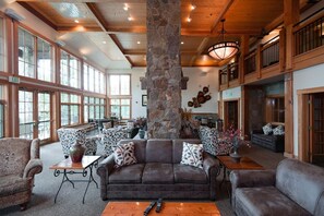 Eine großzügige Lobby mit einer massiven Säule aus Stein, Ledersofas, gemusterten Sesseln und einem Holztisch.
