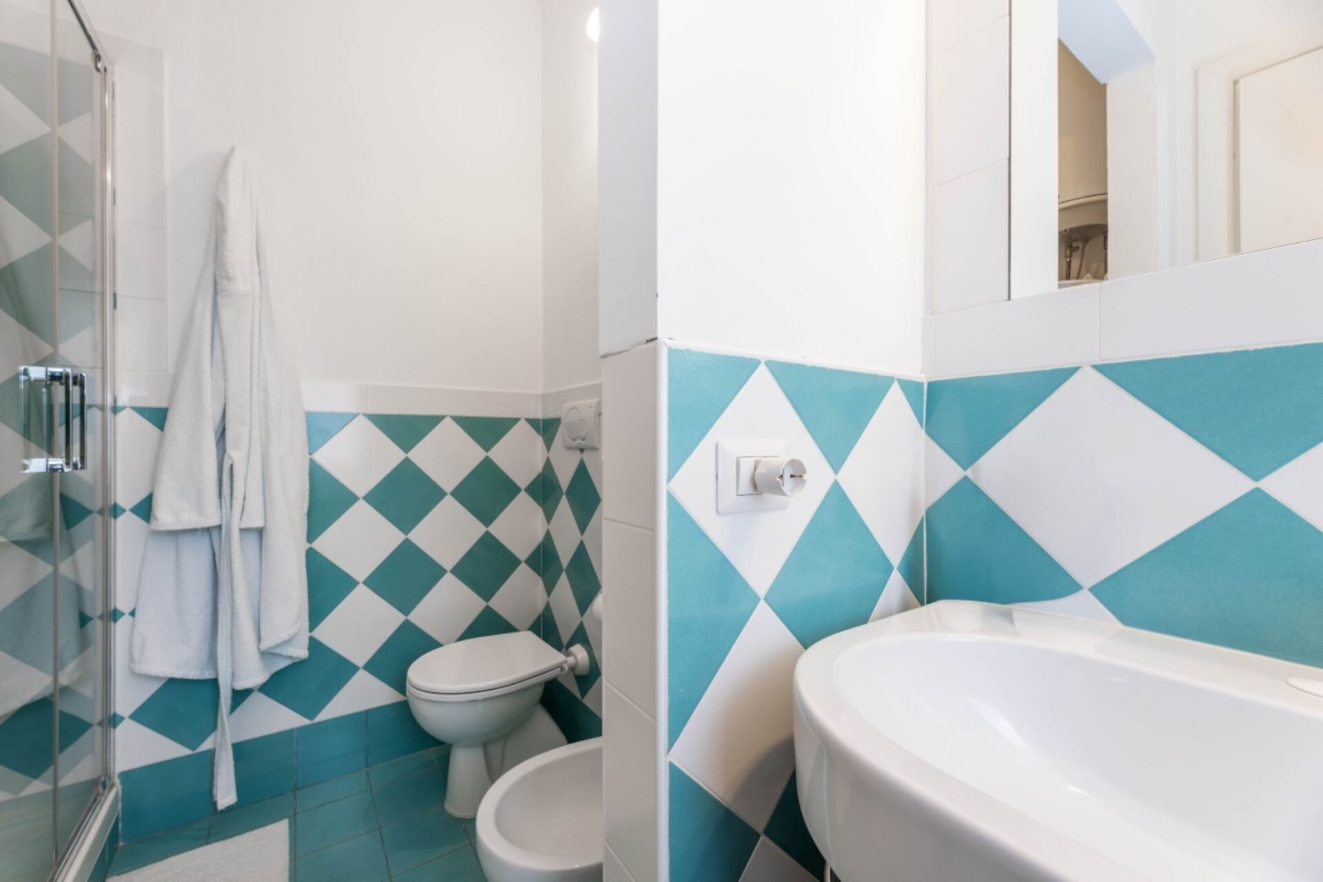 Een badkamer met douche, toilet en wastafel.