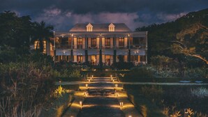 A large, multi-story building with a symmetrical facade, a central staircase, and a well-maintained garden area. - Elegant 3-Bedroom Villa / Sea View & Bel Ombre Setting (Bel Ombre)