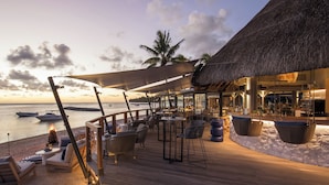 A wooden deck with outdoor seating, a thatched-roof structure, and a view of the ocean. - Elegant 3-Bedroom Villa / Sea View & Bel Ombre Setting (Bel Ombre)