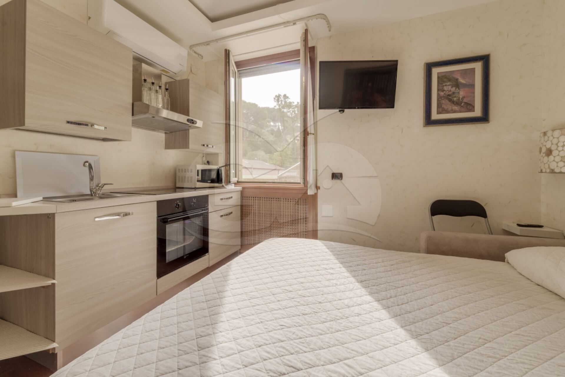 Una camera da letto moderna con un letto grande, una piccola scrivania e un angolo cottura.