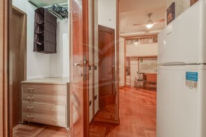 A room with a wooden wardrobe, a white refrigerator, and a dining area with a table and chairs. - Baobab a 100 m dal mare di Campo - Goelba (Campo nell'Elba)
