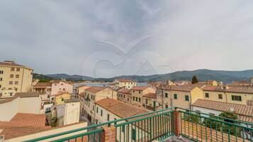 Una località costiera con edifici a tetti in terracotta, vista sul mare e ringhiera in metallo verde.
