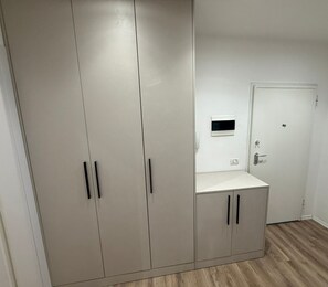 Ein Zimmer mit großem Kleiderschrank, kleinem Schreibtisch und einer Tür.