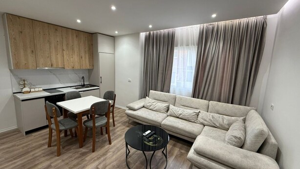 A compact living space with a kitchenette, a sofa, a dining table, and chairs. - Najli apartments (Tiranë)