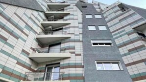 A multi-story building with a distinctive striped facade, balconies, and a ground-level entrance. - Najli apartments (Tiranë)