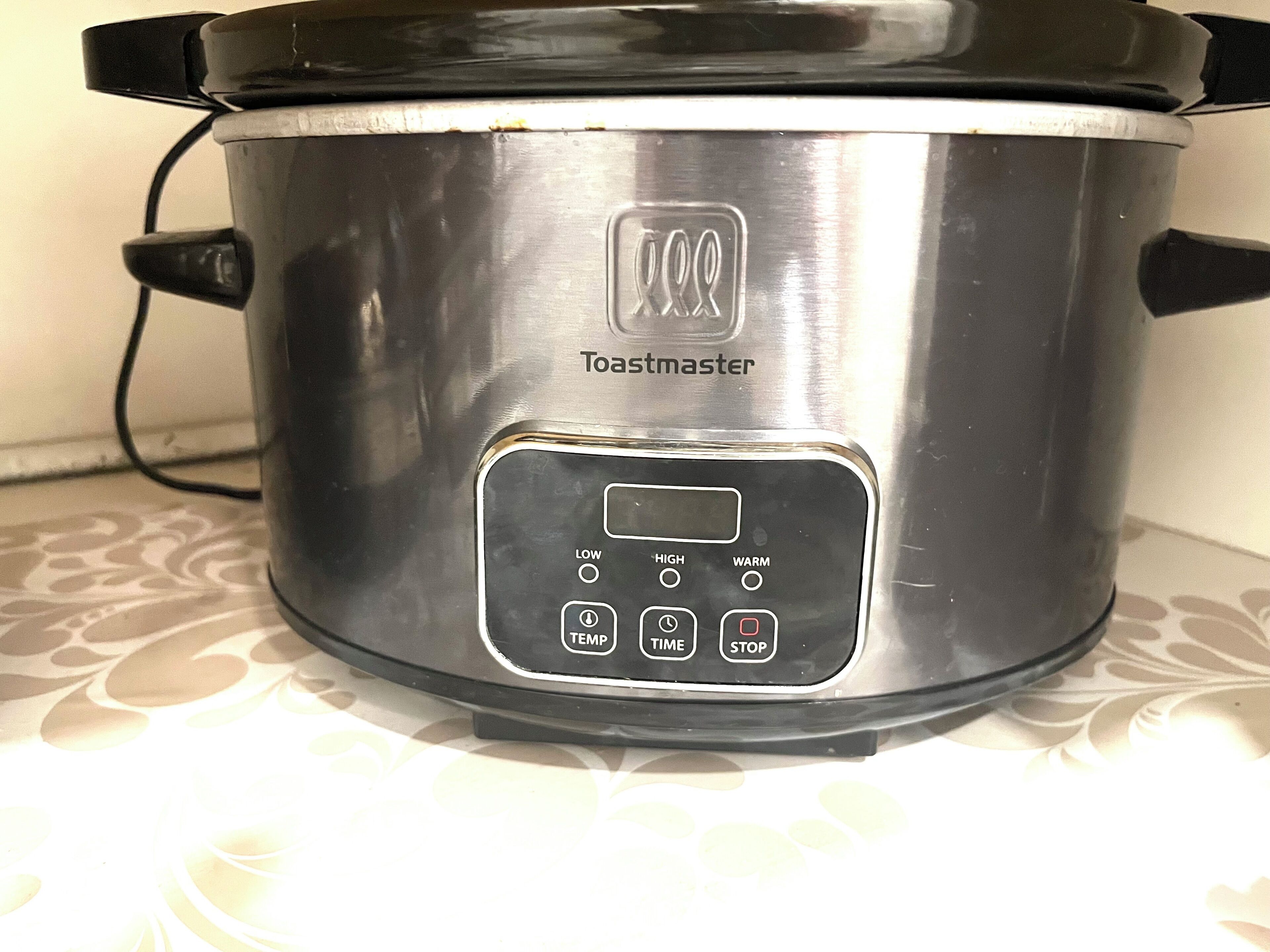 A stainless steel Toastmaster slow cooker with a digital control panel.