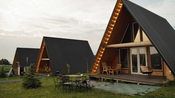 Una cabaña moderna tipo A con terraza, asientos exteriores y ventanas amplias.