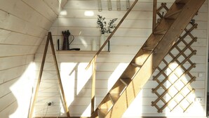 Una escalera de madera con diseño de celosía, un estante pequeño con adornos, y un enchufe en la pared.