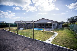 Ein Haus mit Swimmingpool, überdachter Terrasse und einer Steinmauer.