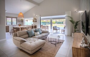 A spacious living area with a large sofa, a coffee table, and a TV mounted on the wall. - Perfect 3-bedroom house with AC in Rivière Noire District (Rivière Noire District)