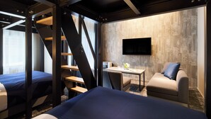 Habitación de hotel con cama, escritorio, silla y televisor montado en la pared.