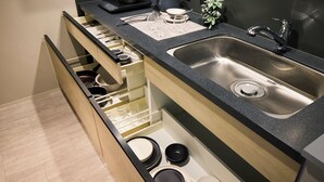 Una cocina con un lavamanos integrado, una encimera y un cajón con utensilios.