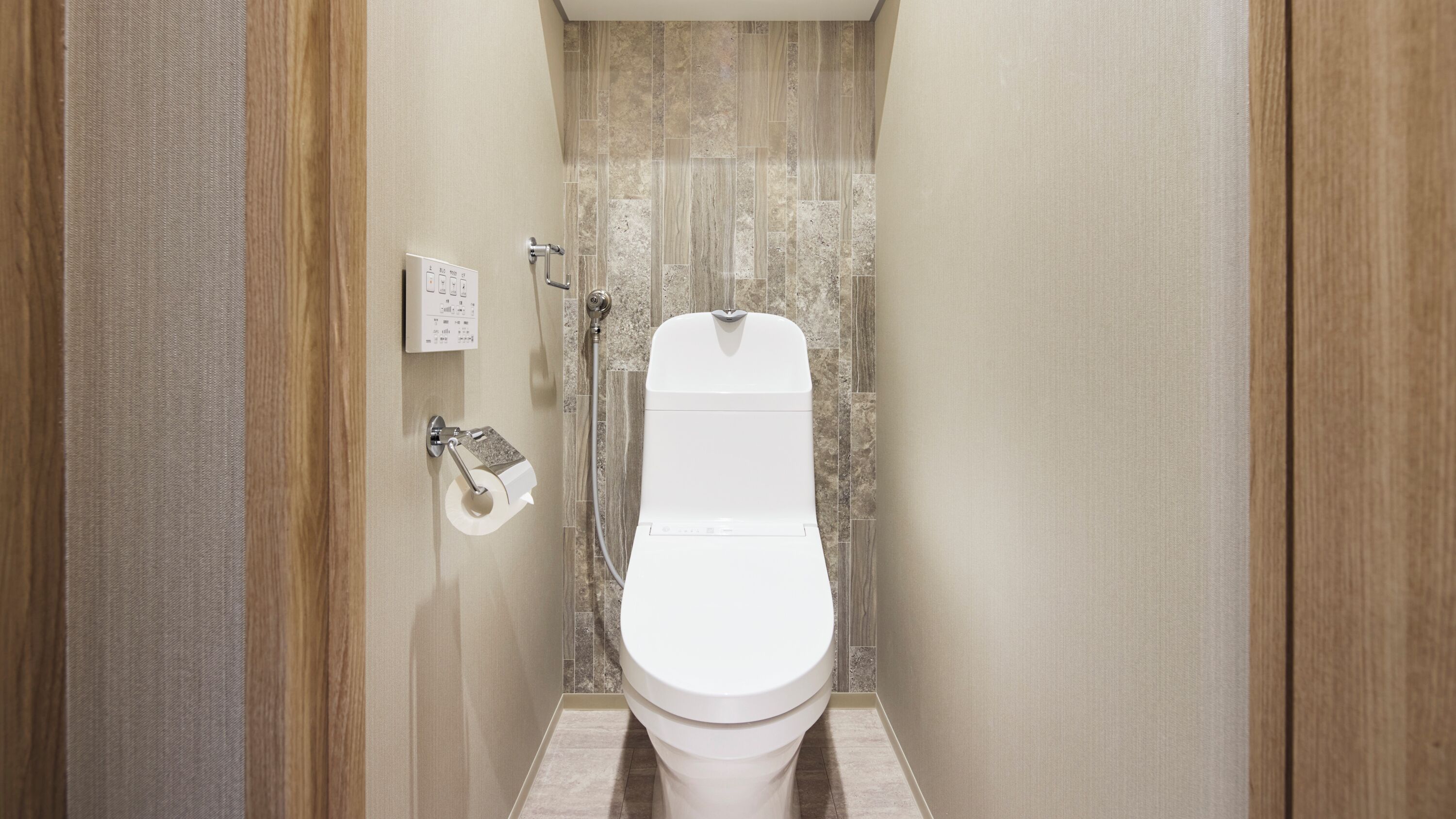 A bathroom with a toilet, a paper towel dispenser, and a shower control panel.