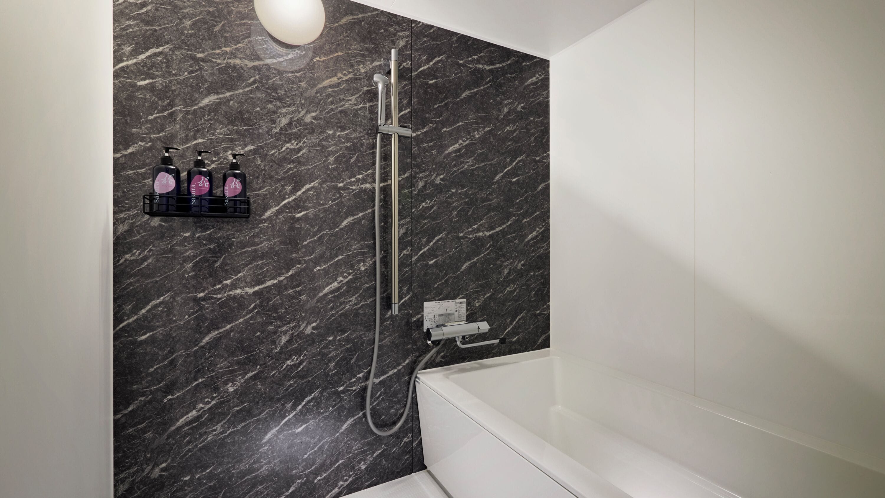 A modern bathroom with a marble wall, a shower, a bathtub, and a soap dispenser shelf.