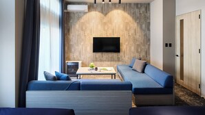 Una habitación de hotel moderna con sofá, una mesita y un televisor instalado en una pared con textura.