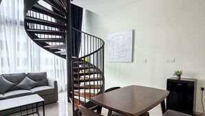 Un salon moderne avec un escalier en colimaçon, une table à manger avec des chaises, un canapé et une table basse.
