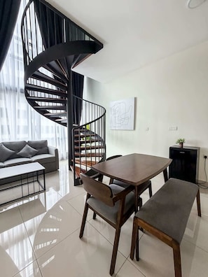 Ein modernes Wohnzimmer mit einer Wendeltreppe, einem Esstisch mit Stühlen, einem Sofa und einem Couchtisch.