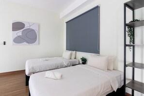 Een moderne hotelkamer met twee bedden, een groot raam, een grijze muur en een minimalistische inrichting.