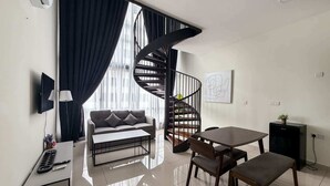 Un salon moderne comprenant un canapé, une table à manger, un téléviseur et un escalier.