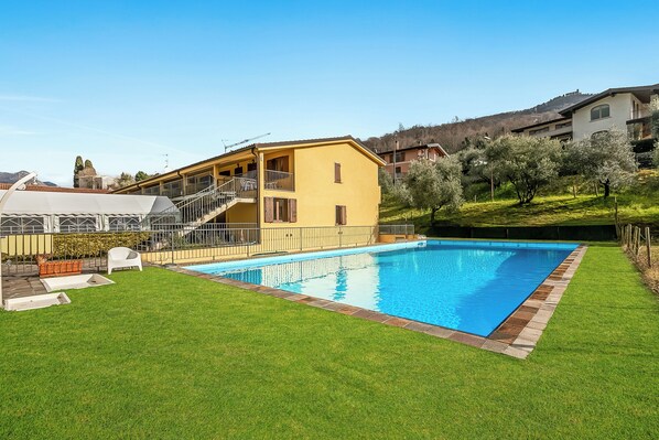 A residential property with a swimming pool, a covered patio, and a well-maintained lawn. - Residence La Perla - Apt 17 (Monte Isola)