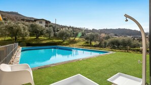 A swimming pool with a clear blue water, surrounded by a well-maintained lawn and olive trees. - Residence La Perla - Apt 18 (Monte Isola)