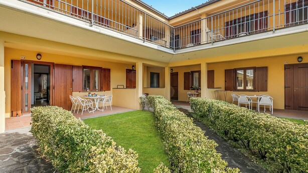 A courtyard with a dining area, two balconies, and a well-maintained lawn. - Residence La Perla - Apt 18 (Monte Isola)