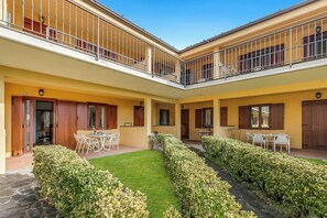 Un cortile con zona pranzo, due balconi e un prato curato.