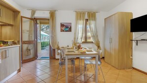 A dining area with a table set for two, a television mounted on the wall, and a wooden wardrobe. - Residence La Perla - Apt 18 (Monte Isola)