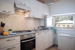 Eine moderne Küche mit hellen Holzschränken, einem Gasherd und einem eingebauten Backofen.