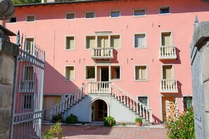 Ein pinkfarbenes Gebäude mit einer zentralen Treppe, zahlreichen Fenstern und einem verschlossenen Eingang.