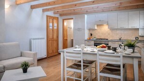 A modern kitchen with white cabinets, a dining table with four chairs, and a wooden ceiling. - Nuvolau Appartement Dolomites (Perarolo di Cadore)