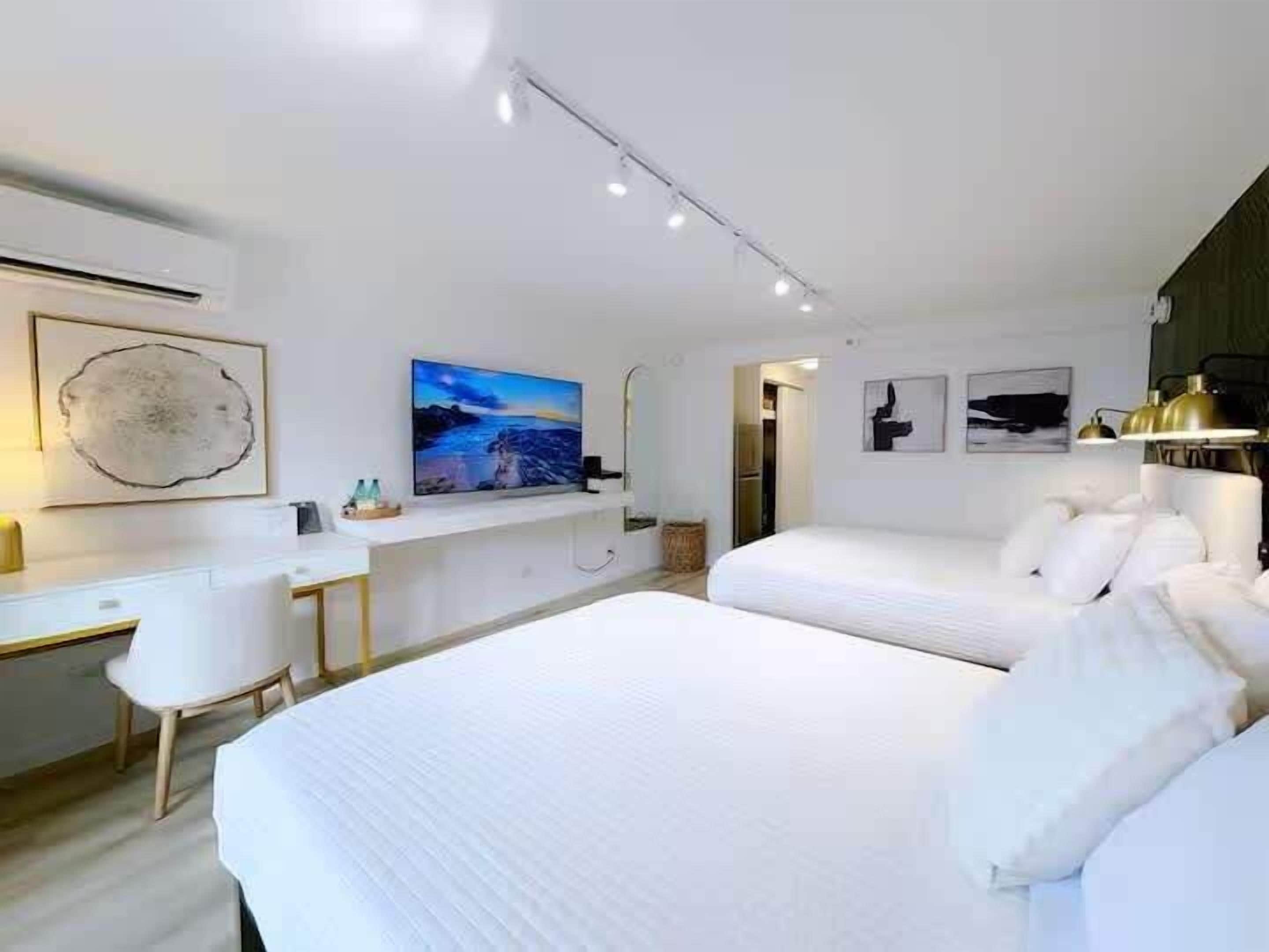A modern hotel room with a large bed, a desk, and a painting on the wall.