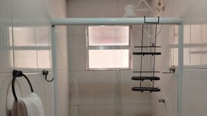 A glass-enclosed shower with a towel rack, a small window, and a toilet. - Suite Da Praia Ar-conditioned (Rio de Janeiro)