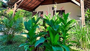 Ein traditionelles, reetgedecktes Gebäude mit schlichtem, offener Bauweise, umgeben von üppiger tropischer Vegetation.