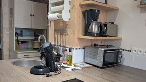 Een kleine keuken met een inbouwfornuis, een magnetron en een spoelbak.
