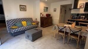 A living room with a sofa, ottoman, and a dining area with chairs and a table.