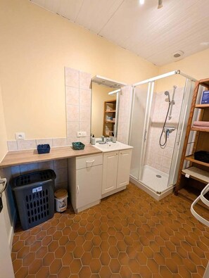 A bathroom with a shower, sink, and storage cabinets. - The source - Le Grand-Pressigny (Le Grand-Pressigny)