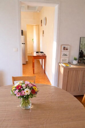 A dining area with a round table, a vase of flowers, and a wooden cabinet with a mirror. - The source - Le Grand-Pressigny (Le Grand-Pressigny)