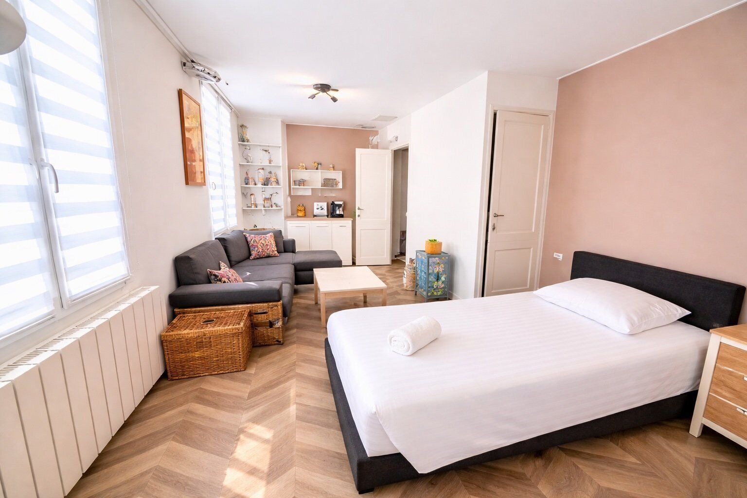 A bedroom with a bed, a sofa, a small table, and a chest of drawers.