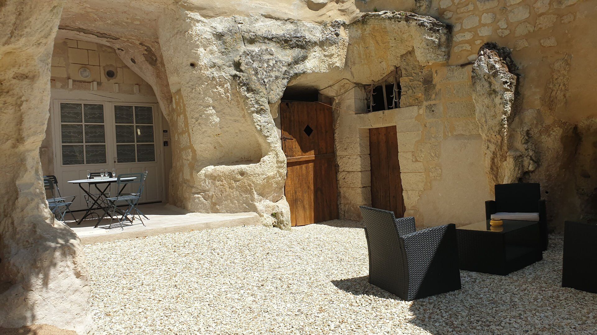 Interior rústico de piedra con comedor, una puerta de madera y una ventana con celosías.